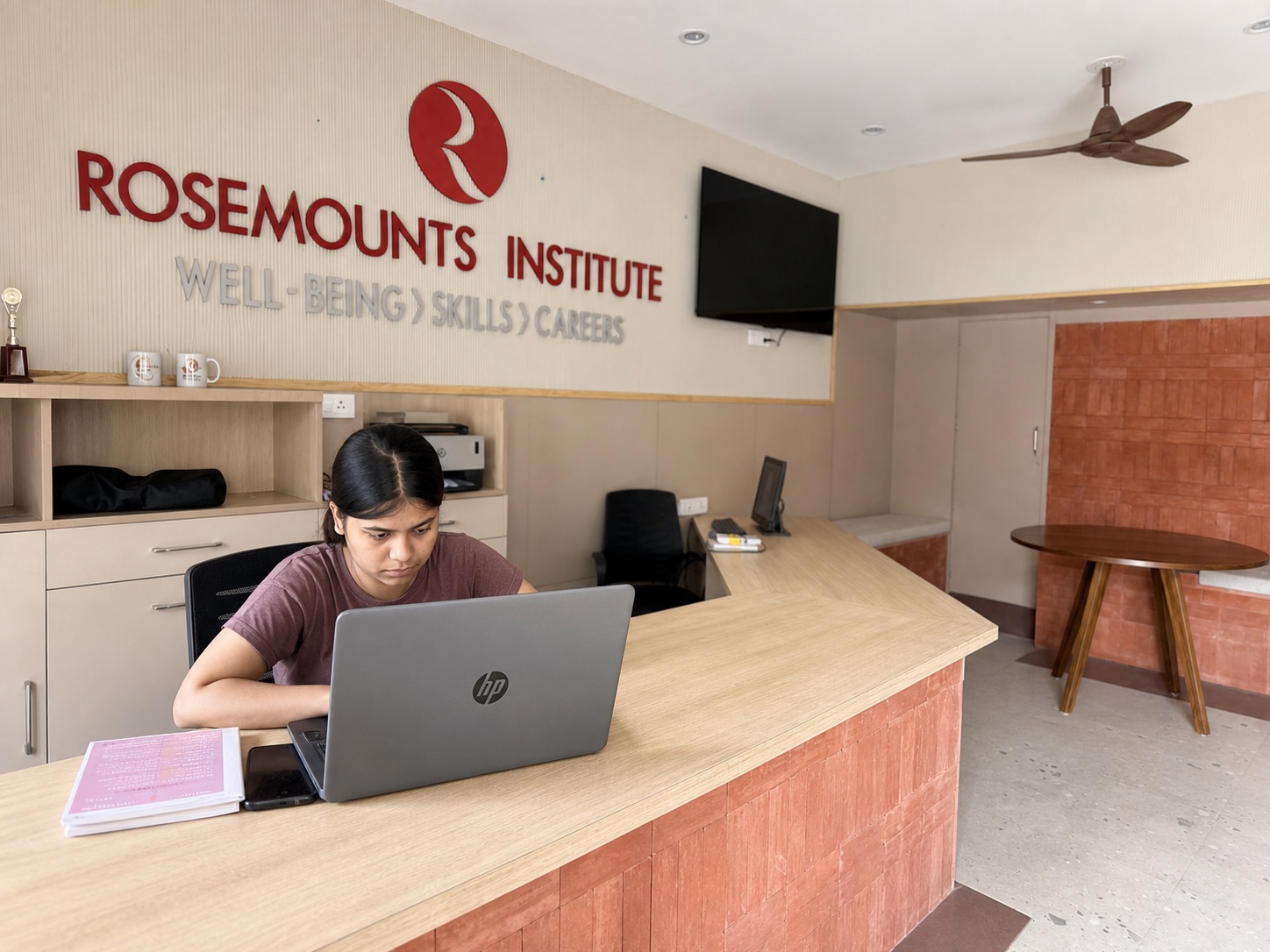 A student studying on a laptop at the Rosemounts Institute reception in Dehradun